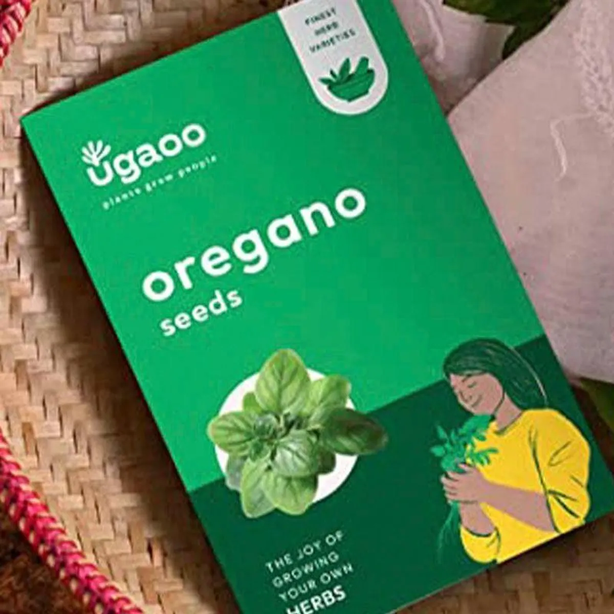 Close-up of green oregano seed pack with botanical and figure illustration
