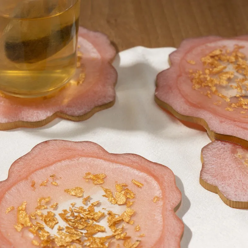 Close-up of pink coasters with gold detailing beside a glass mug