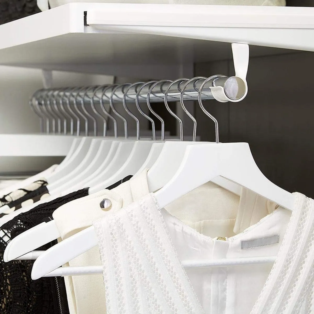 White hangers holding garments inside a wardrobe