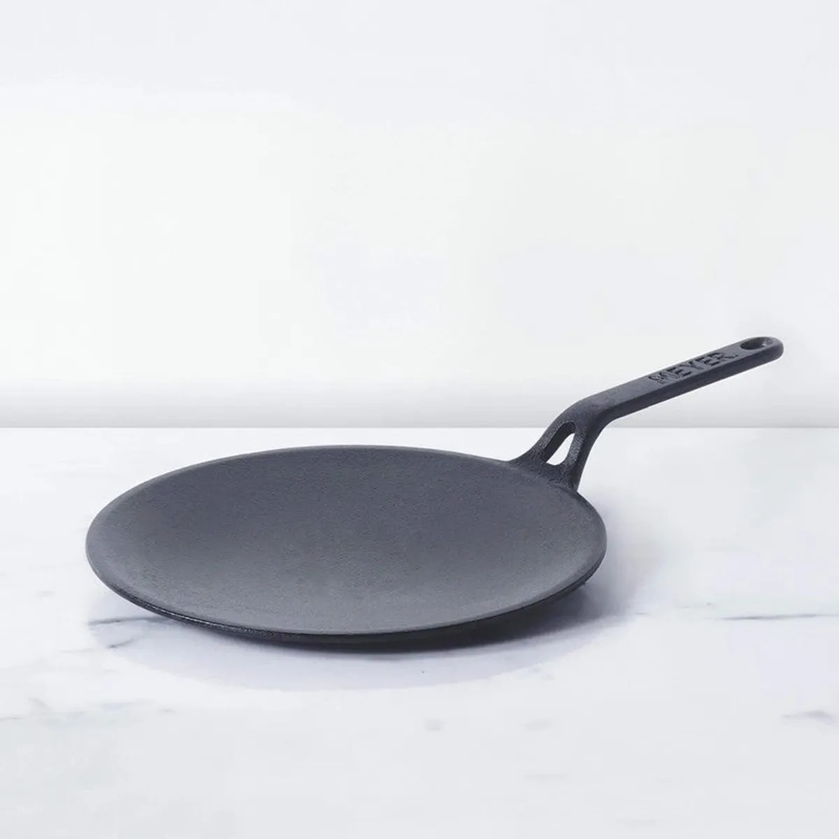 Black cast iron roti tawa shown against a light background