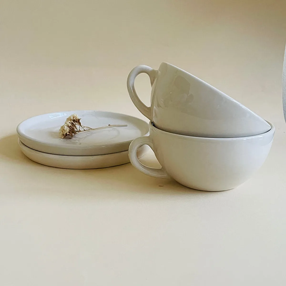 White ceramic cups stacked with saucers in a minimalist arrangement