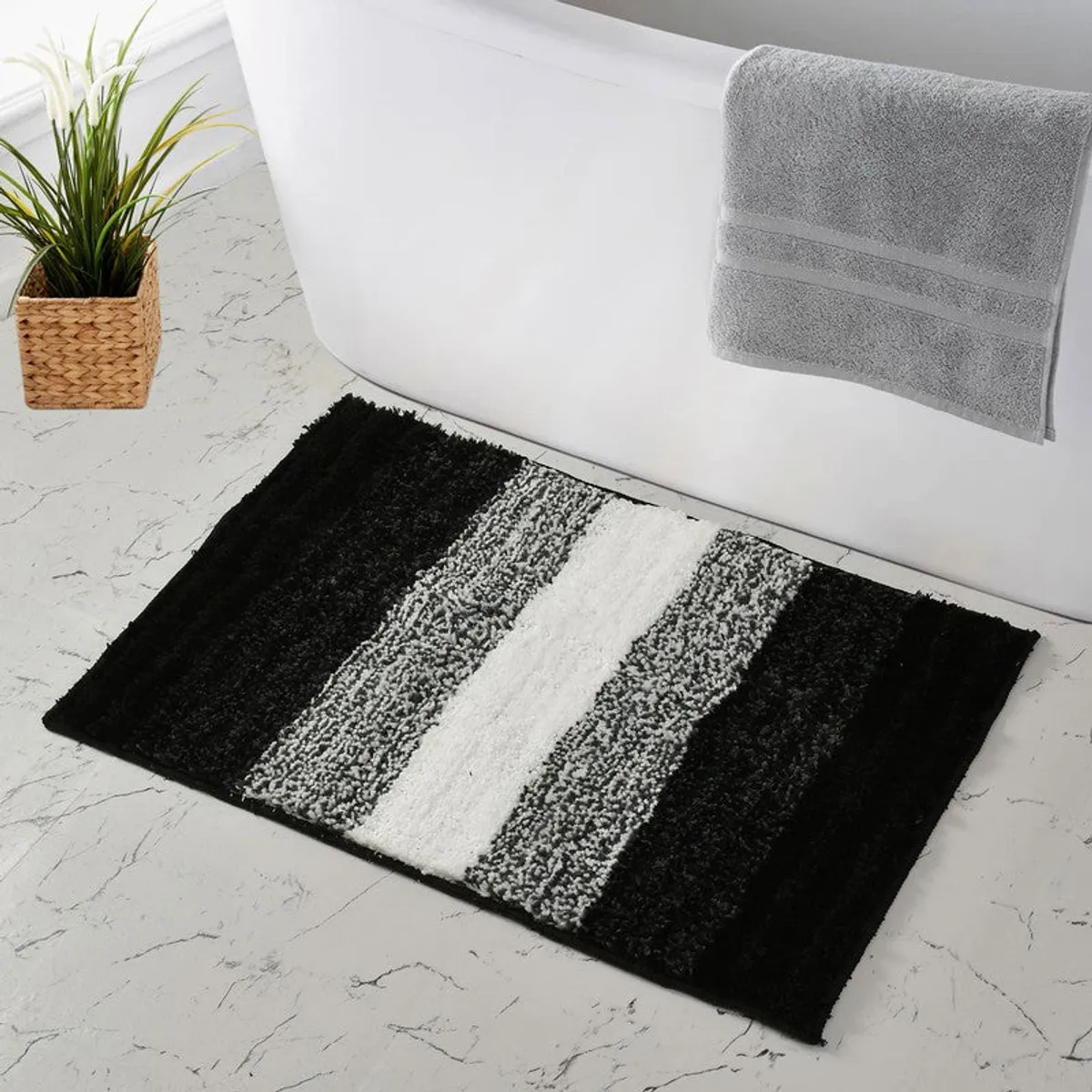 Black and white striped bath mat beside a white bathtub
