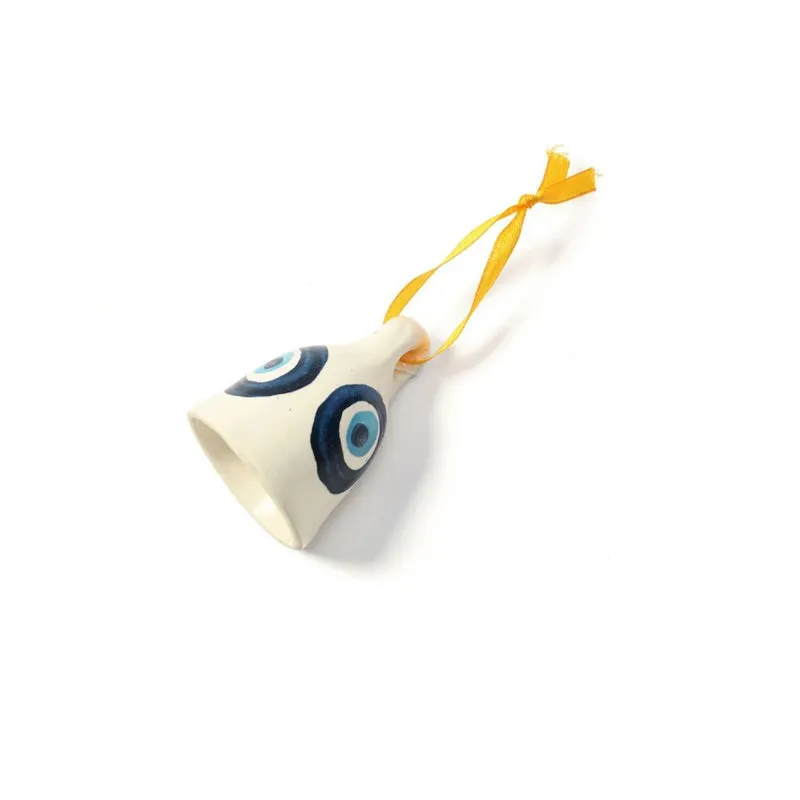 White ceramic hanging bell with blue evil eye motifs and yellow ribbon on a plain background