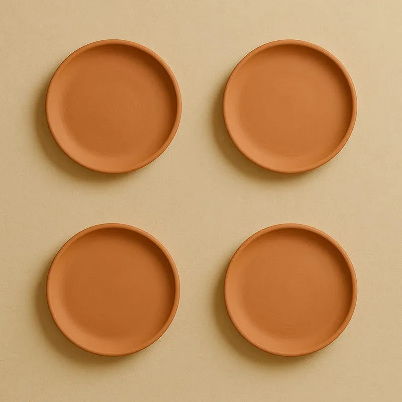 Four round terracotta plates arranged on a neutral wall