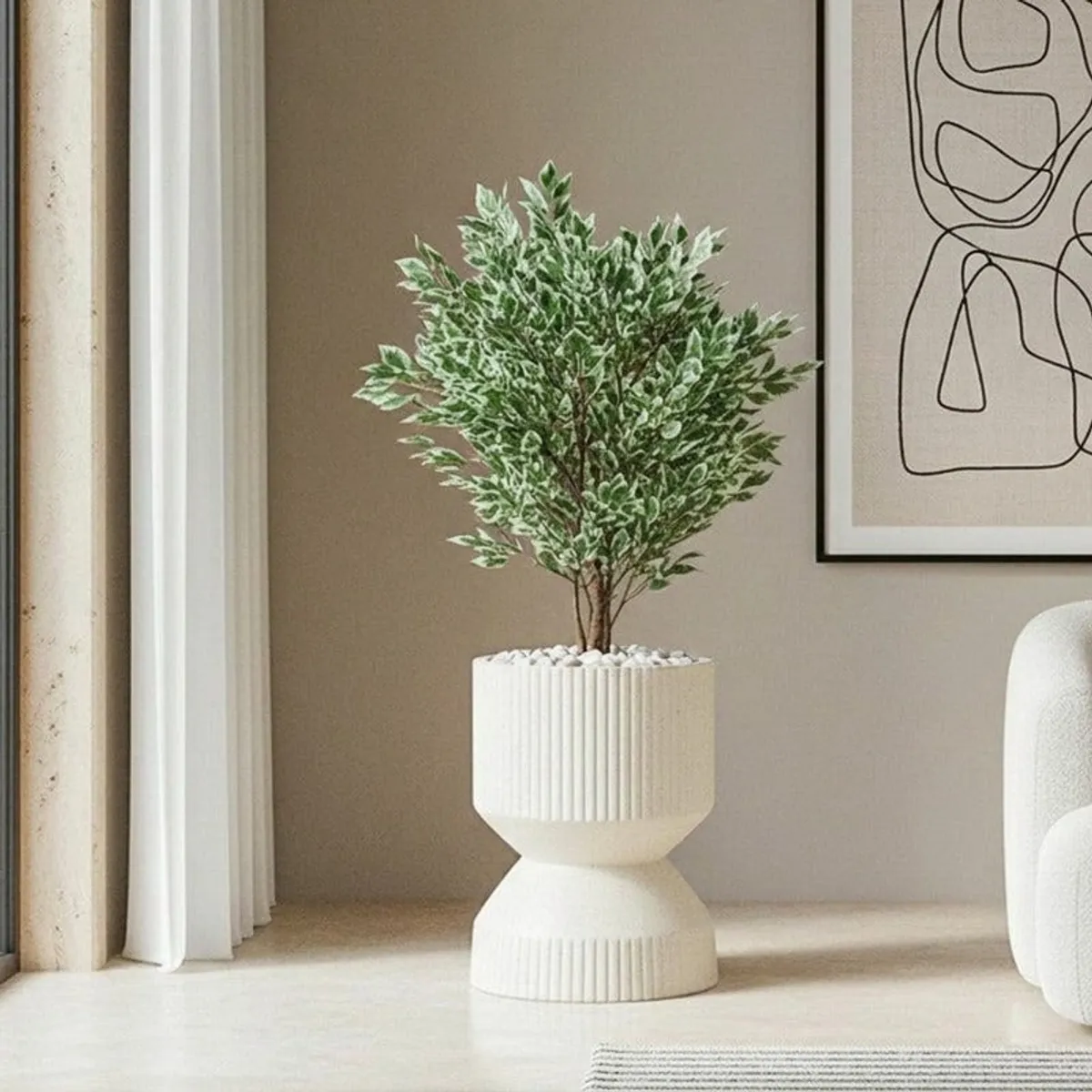 Off-white ribbed planter holding a leafy plant beside framed wall art.