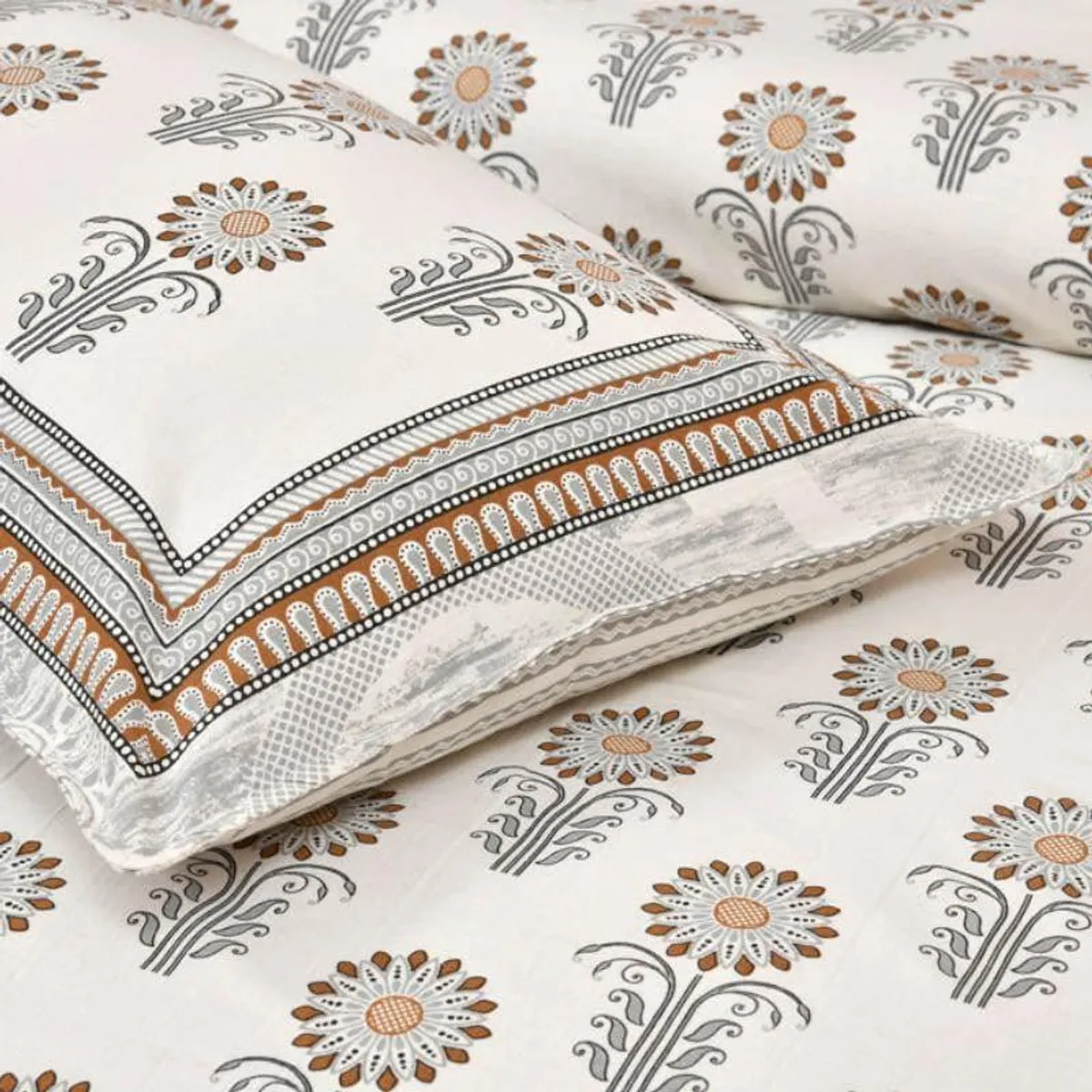 Close-up of pillow cover with grey and brown floral print and bordered edge