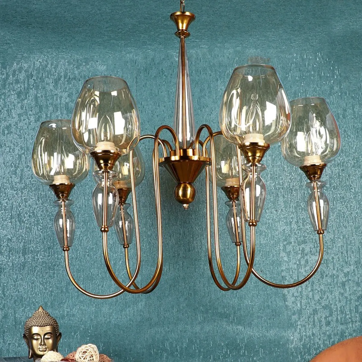 Gold chandelier with clear glass shades shown against a blue textured wall