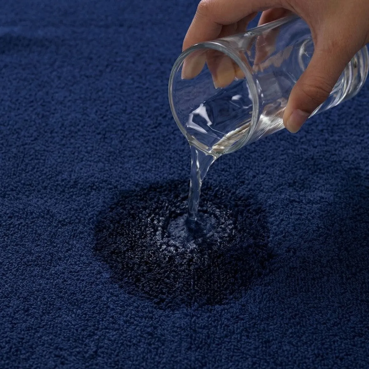 Water being poured onto a navy towel surface