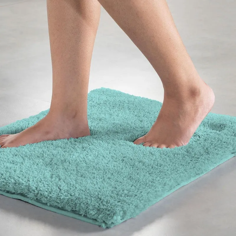 Feet standing on a sea blue plush rectangular bath mat