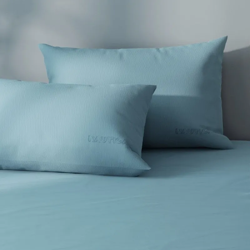 Close-up of blue satin cotton bedding and pillows with subtle Nautica detailing