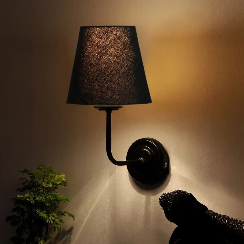 Black wall lamp glowing warmly against a wall