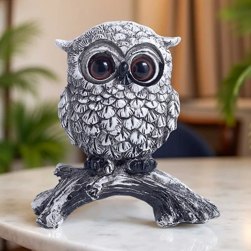 Silver owl figurine displayed on a tabletop in a living room setting