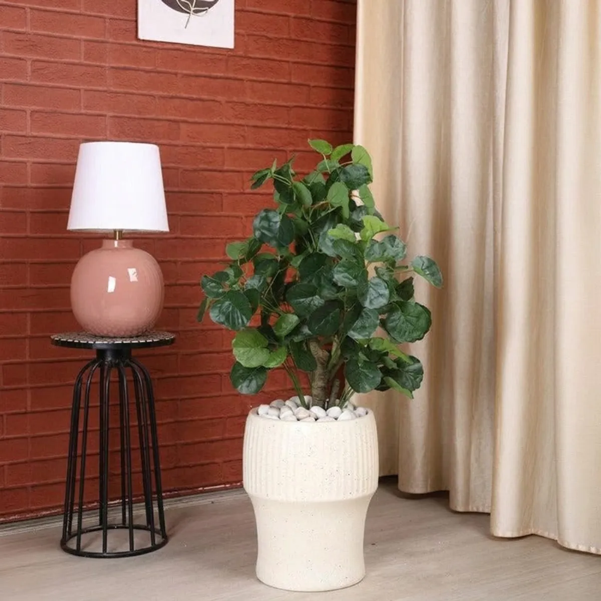 White ribbed planter with a leafy plant against a brick wall