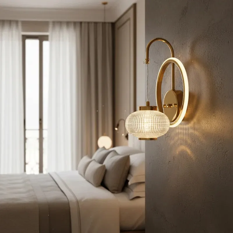 Close view of a glowing ring wall lamp with crystal globe beside a bed.