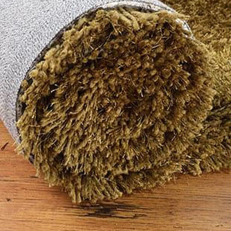 Close-up of the olive-green rug's long, plush shag pile and rounded edge
