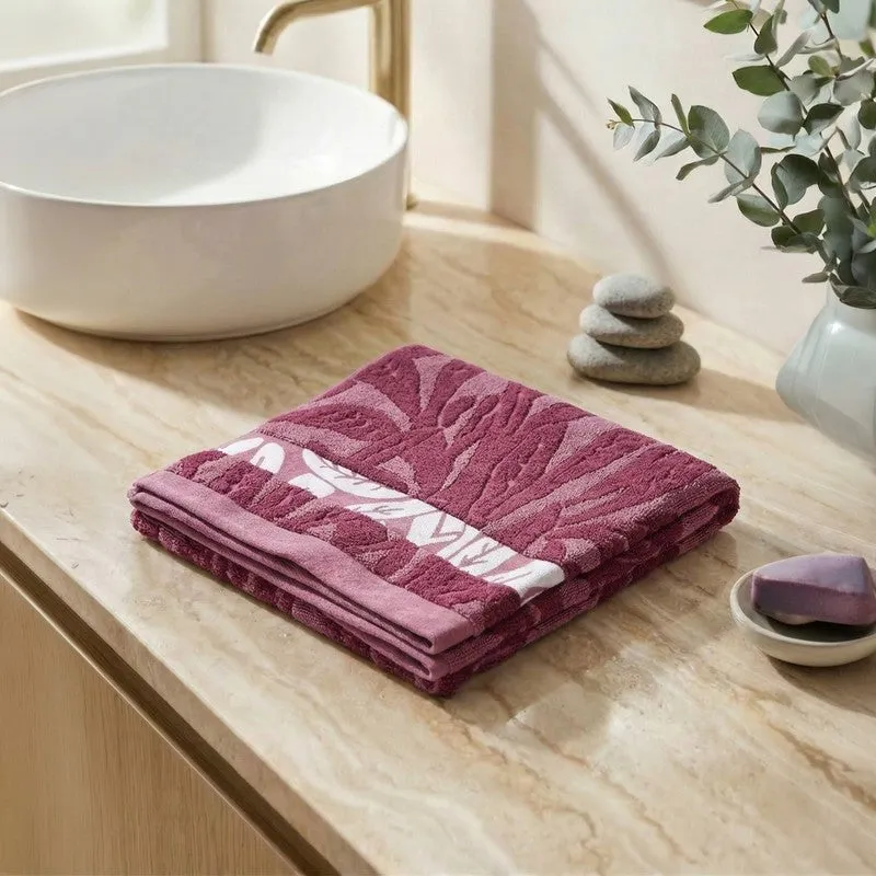 Folded maroon floral bath towel on a bathroom counter.