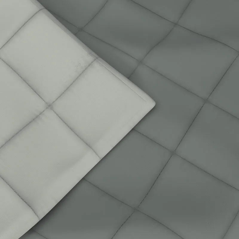 Close-up of grey and ivory reversible comforter with quilted square pattern