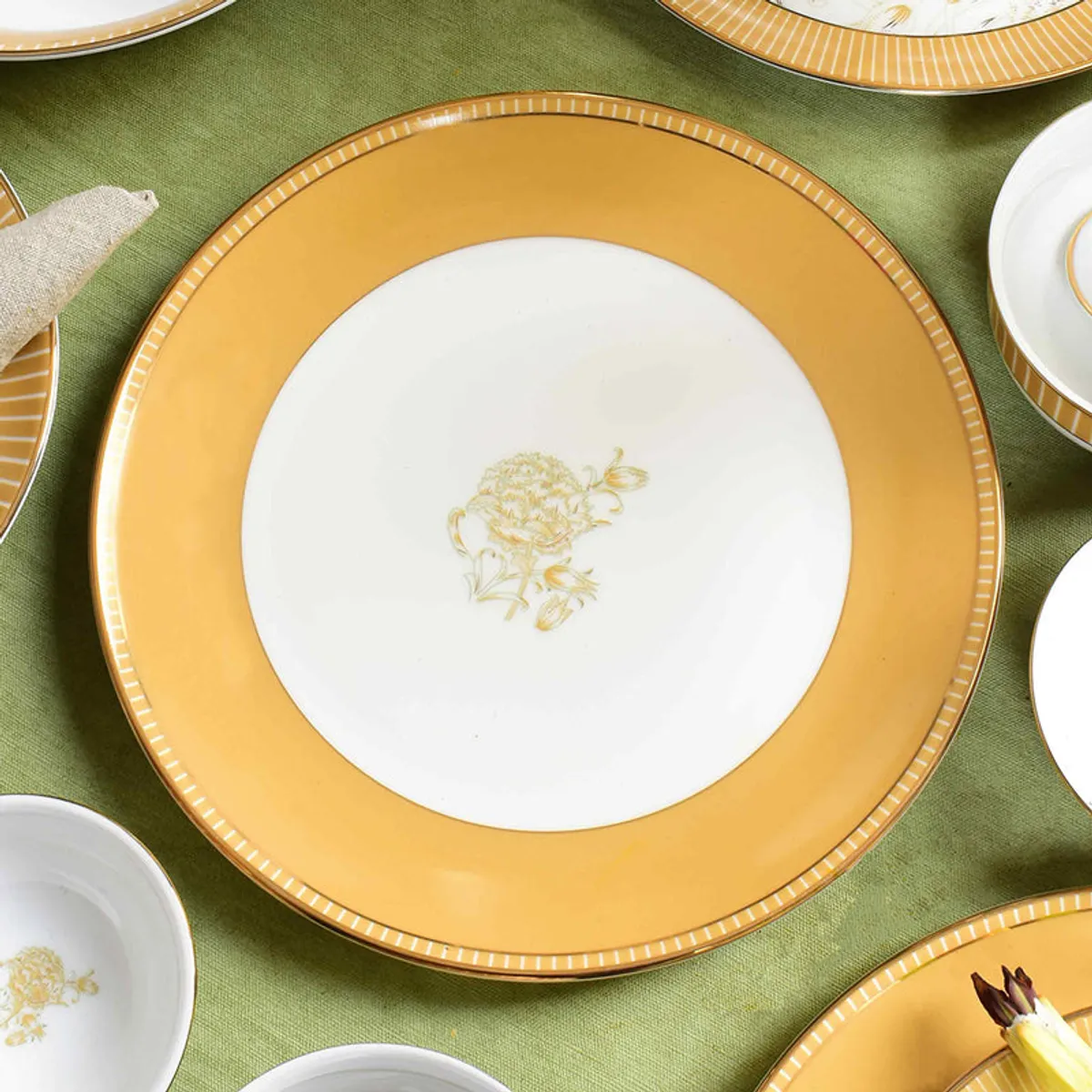 Close-up of a glossy mustard dinner plate with gold floral centre detail