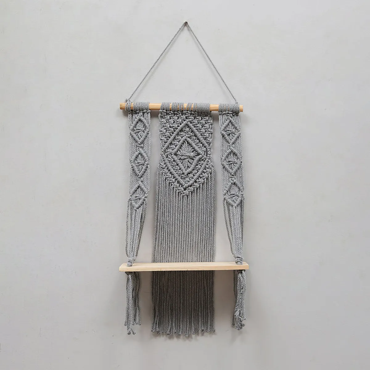 Grey macrame wall shelf shown empty against a wall