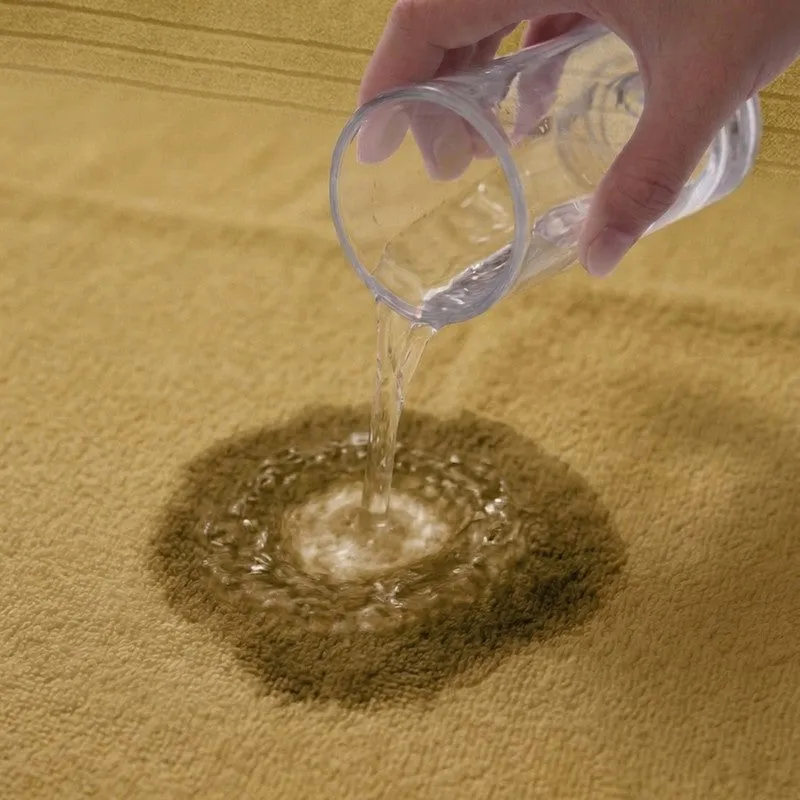 Water being poured onto an olive green towel surface