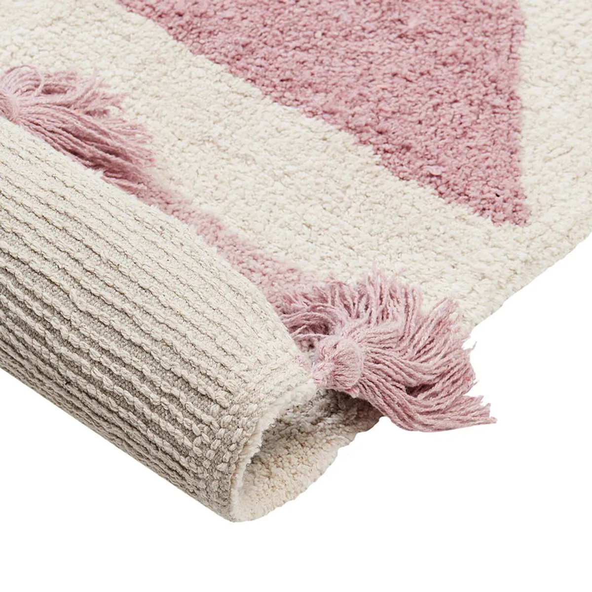 Rolled corner showing the rug's tufted surface and pink tassel detail