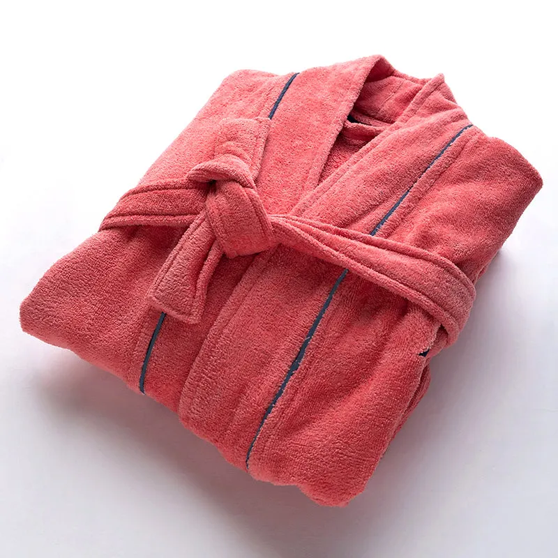Folded peach bath robe with navy piping on a white surface