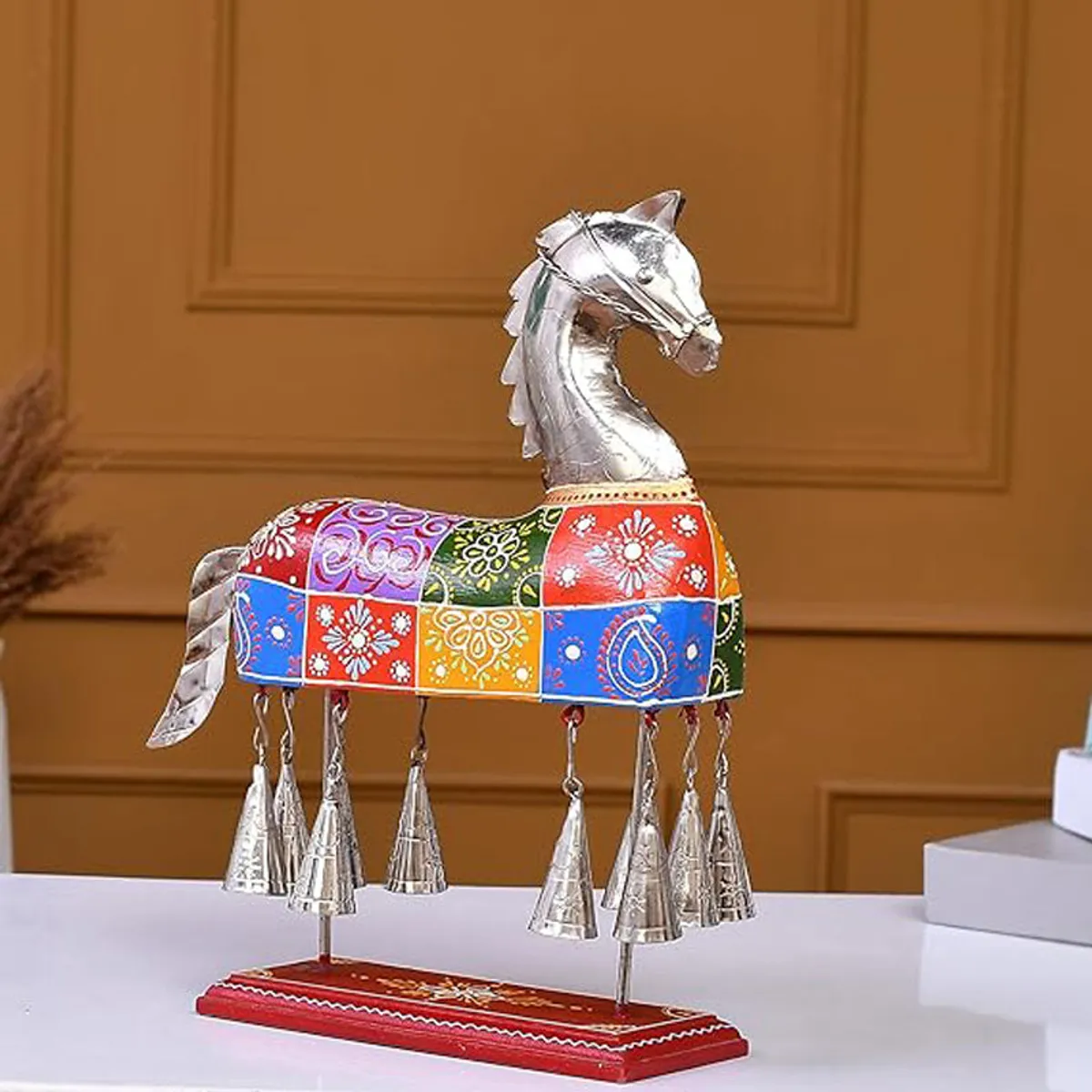 Angled side view of a multicolour horse showpiece with silver head and bells