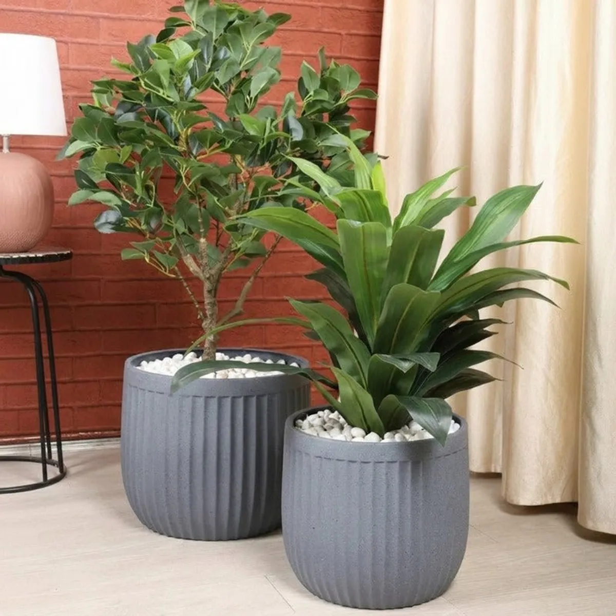 Two grey ribbed planters with green plants in an indoor setting.
