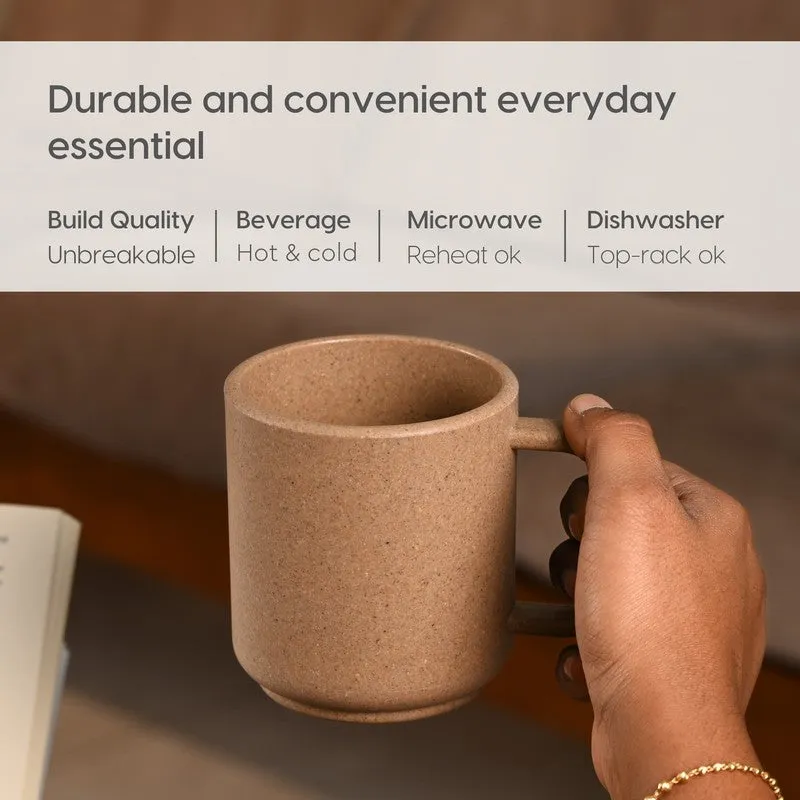 Hand holding a brown mug in a warm indoor setting