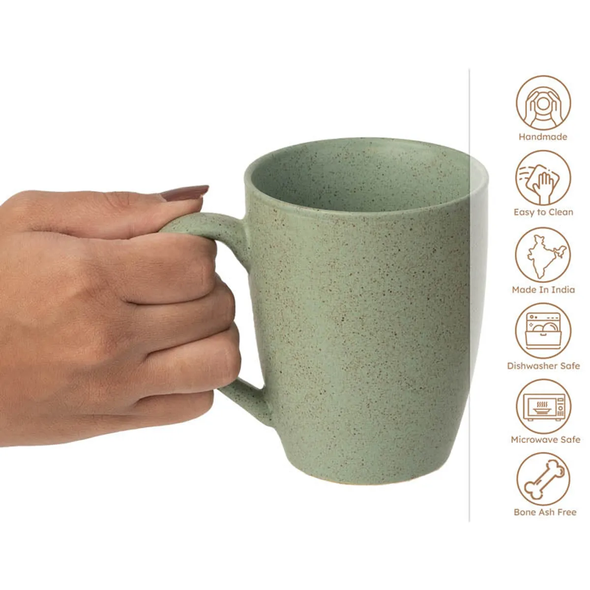 Green ceramic mug shown in close-up with a hand holding its handle.