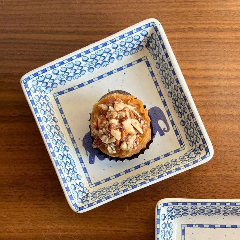 Square ceramic platter with blue floral border holding a dessert on a wooden table