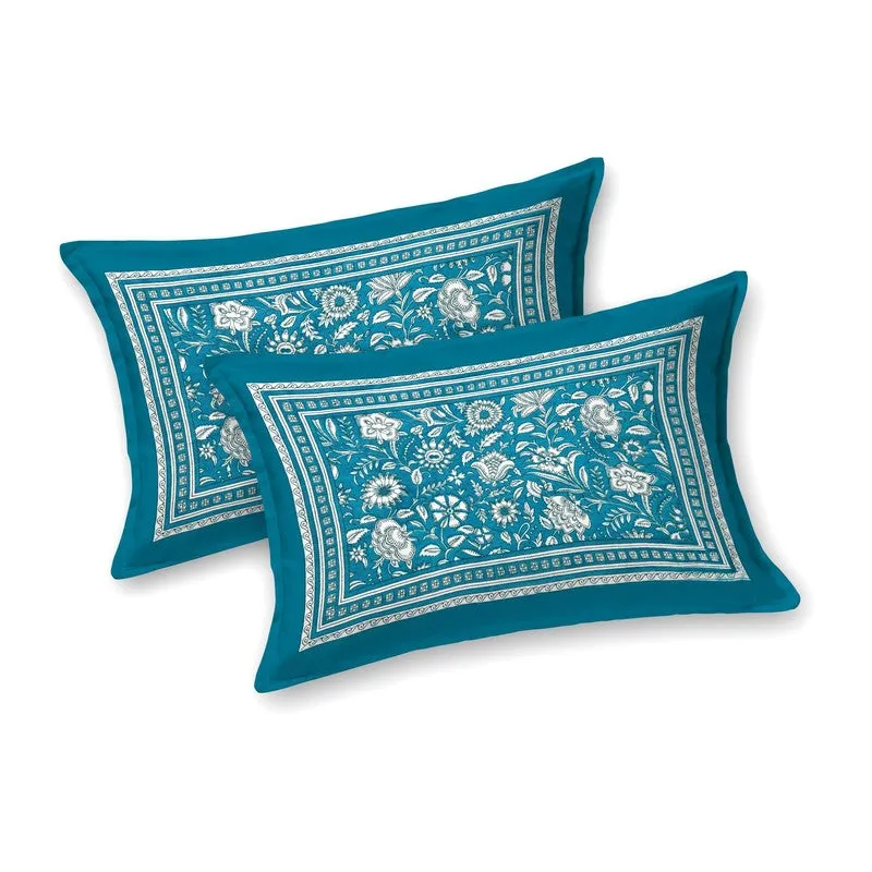 Two matching teal pillow covers with white floral detailing on a plain background.