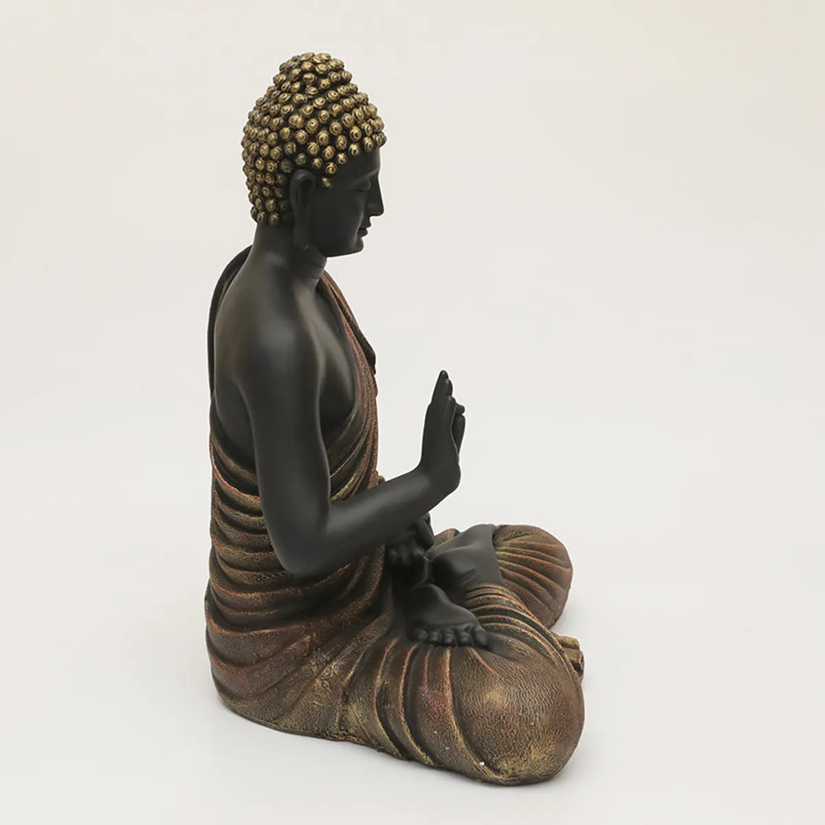 Side view of the seated black and brown Buddha idol with flowing robe.
