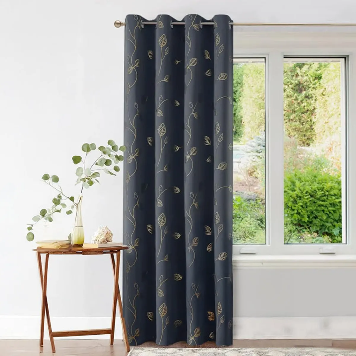 Charcoal-black curtain with gold leaf motifs hanging beside a bright window