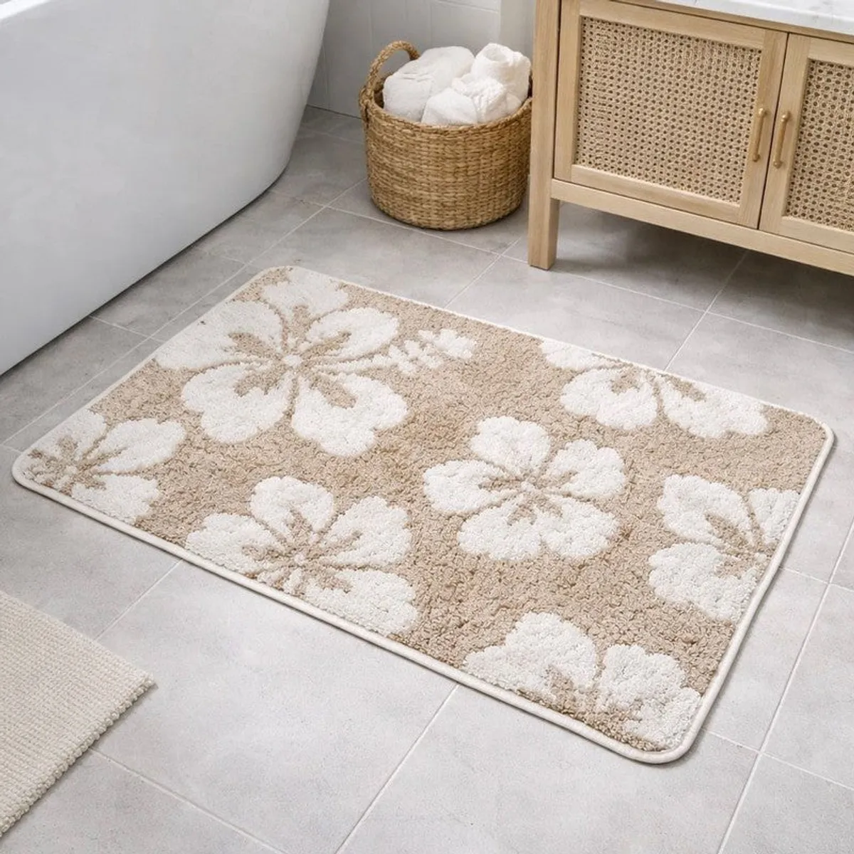 Beige and white floral bath mat beside a bathtub and bathroom cabinet
