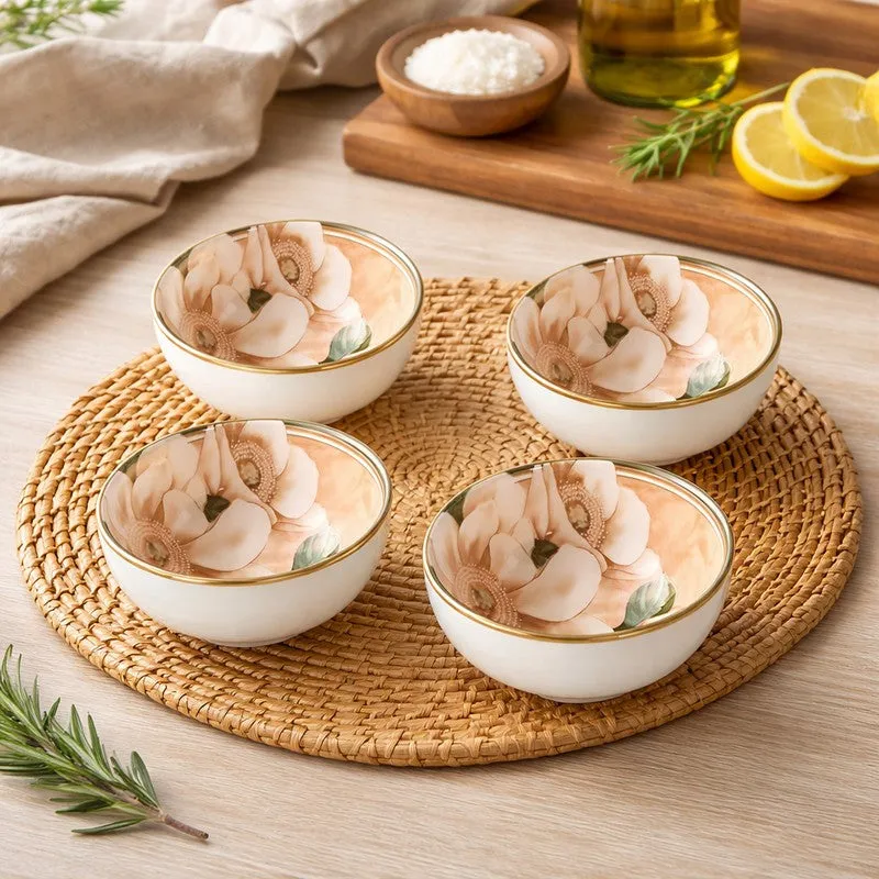 Four beige ceramic bowls with floral interiors arranged on a woven dining mat