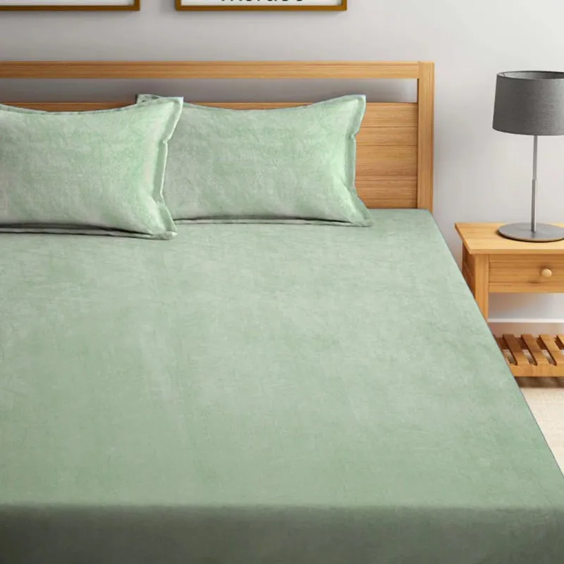 Close view of sea green bedsheet spread on a bed with matching pillow covers