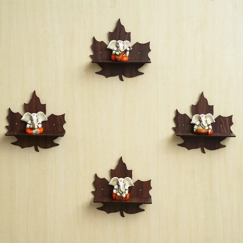 Set of four brown leaf-shaped wall accents with Ganesha motifs on a cream wall