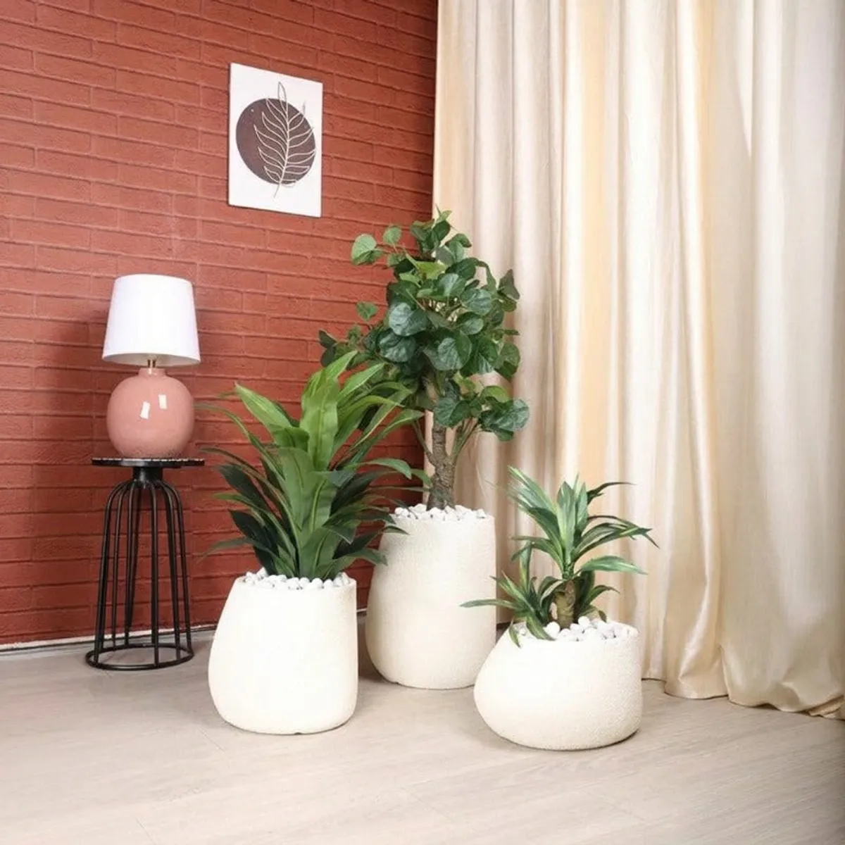 Three white planters with plants arranged in a living room corner
