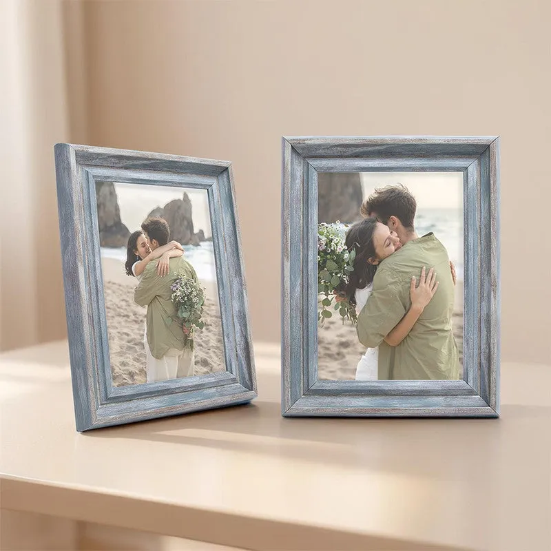 Two blue-grey tabletop photo frames arranged on a light console