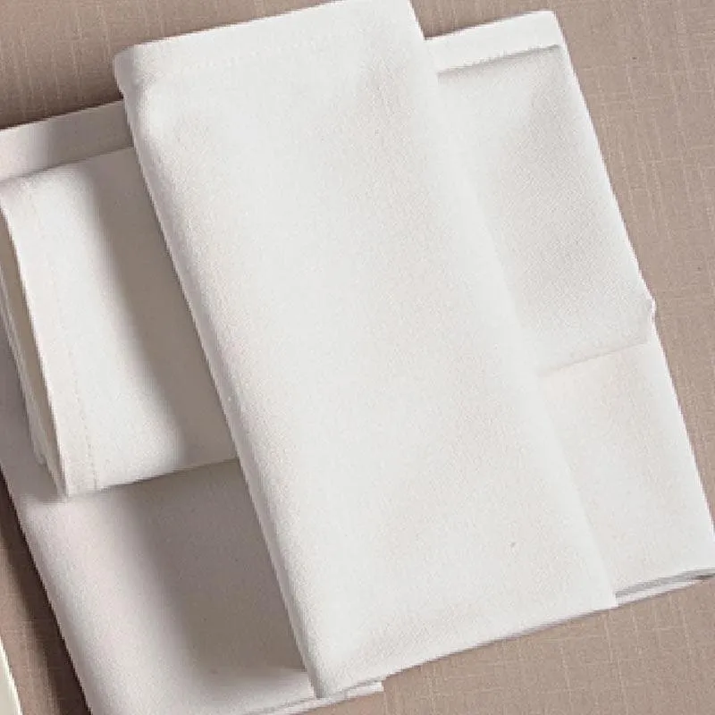 Close-up of folded ivory dinner napkins stacked on a neutral surface