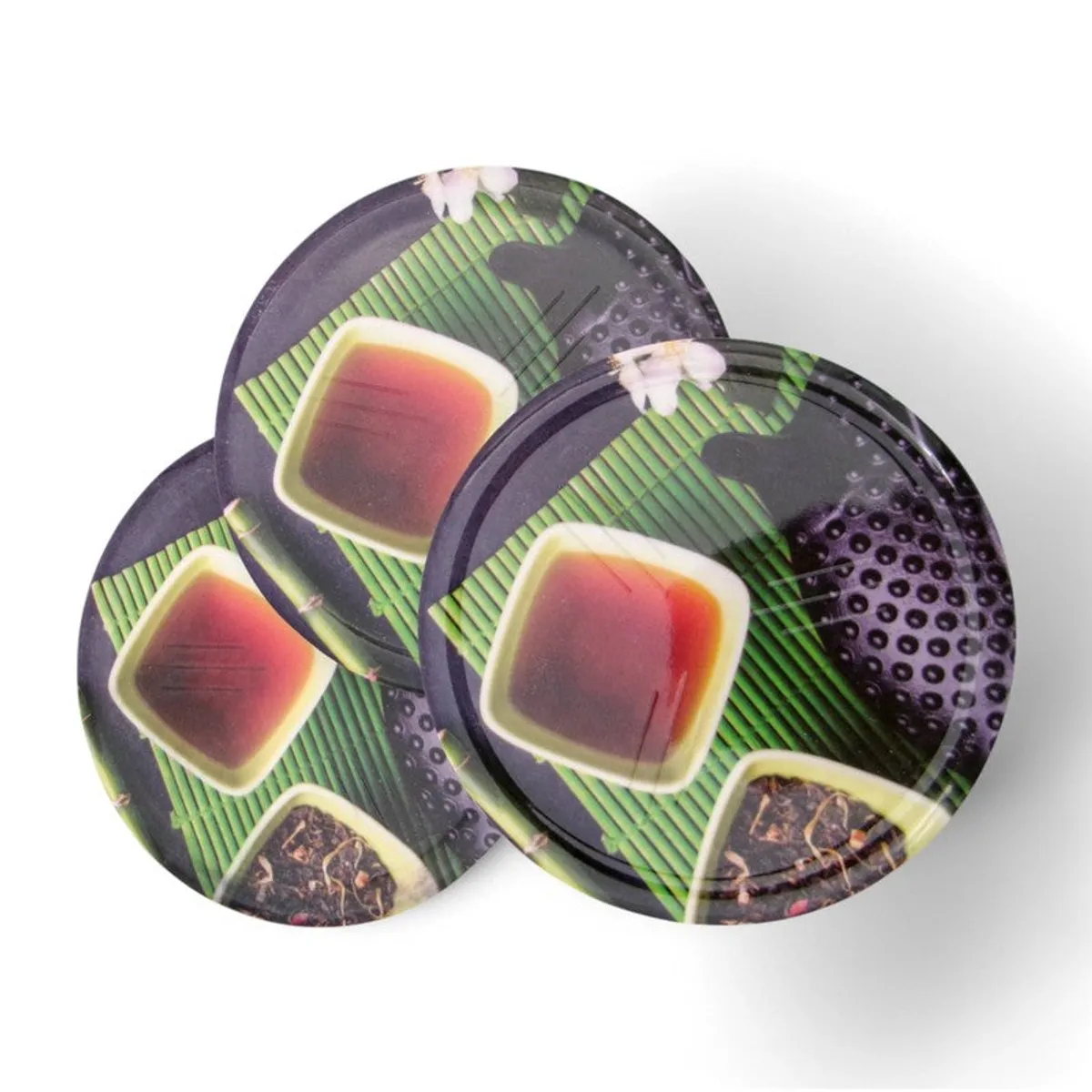 Three round coasters with a multicolour tea-inspired motif overlapping on a white background
