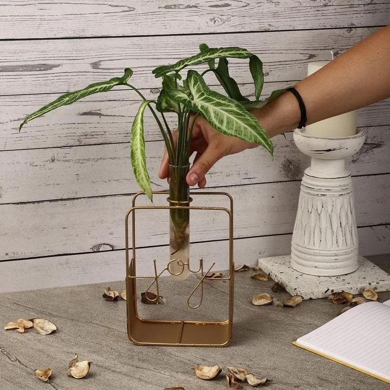 Gold-toned testube planter styled with leafy stems on a tabletop
