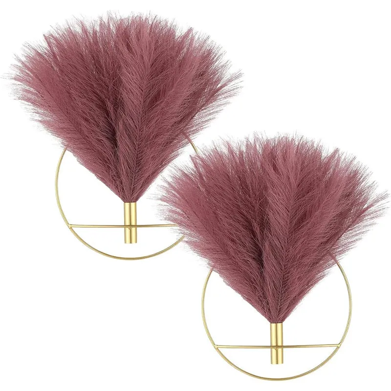 Set of two gold circular wall vases with fluffy mauve stems on a white background
