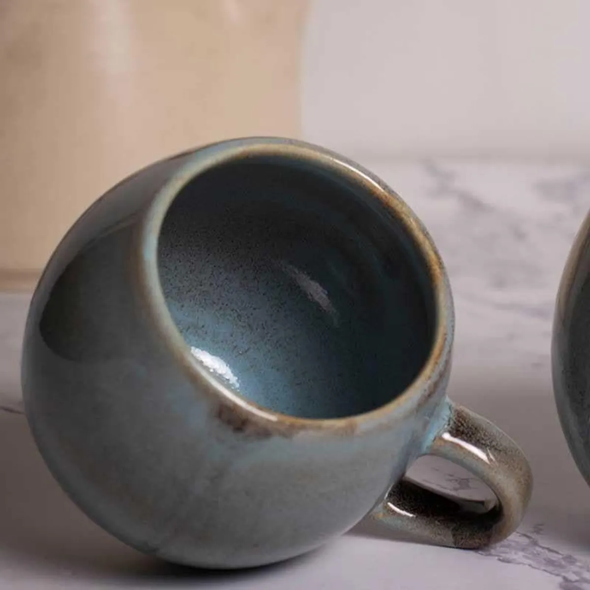 Close-up of a rounded grey speckled mug with a brown-edged rim and handle