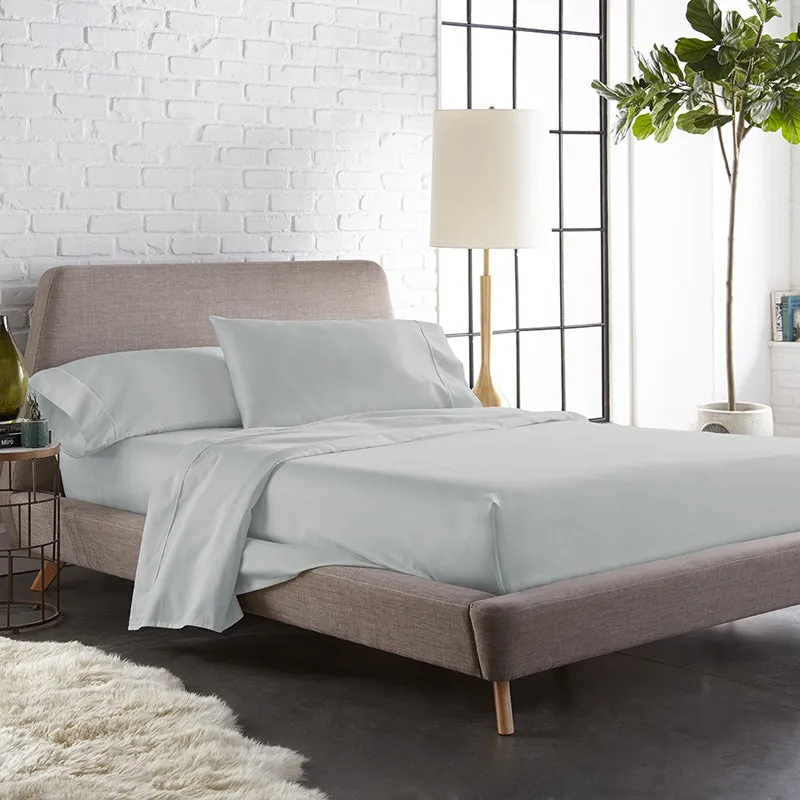 Light grey fitted bedsheet with matching pillow covers on a modern upholstered bed