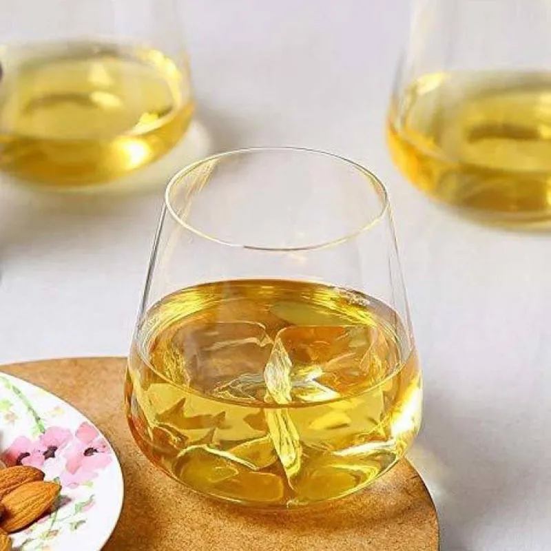 Clear whiskey tumbler filled with golden whiskey and ice beside snacks.