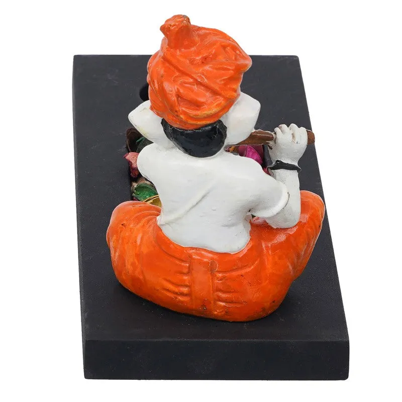 Back view of seated Ganesha figurine on a black rectangular candle holder base
