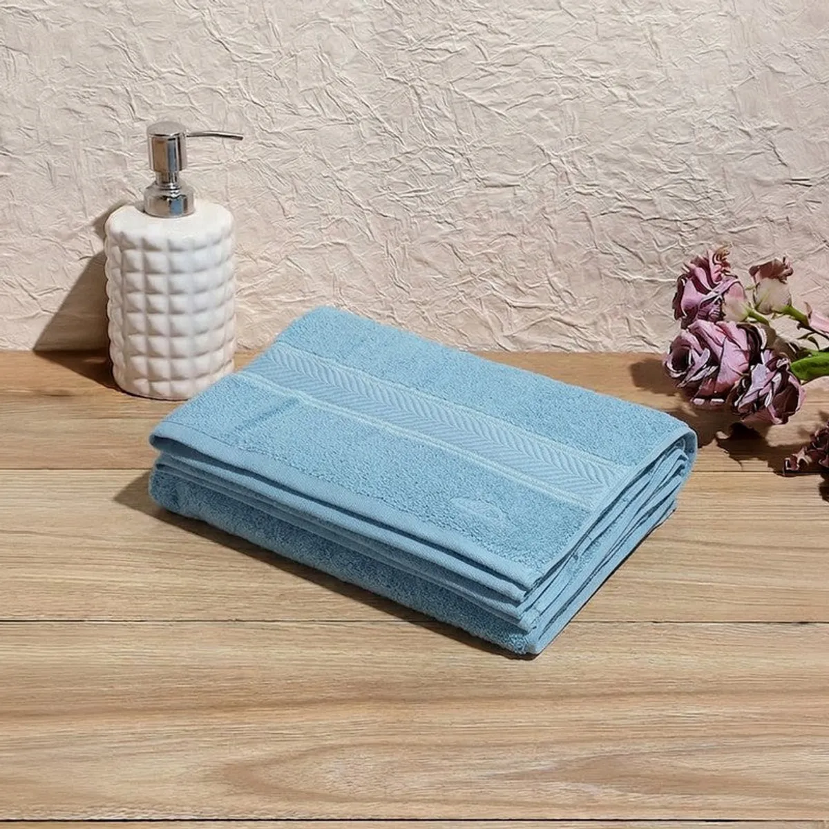 Folded dust blue bath towel displayed on a wooden table