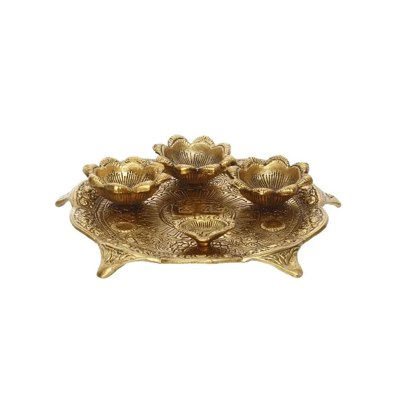 Front view of round gold pooja thali with raised floral holders and embossed surface